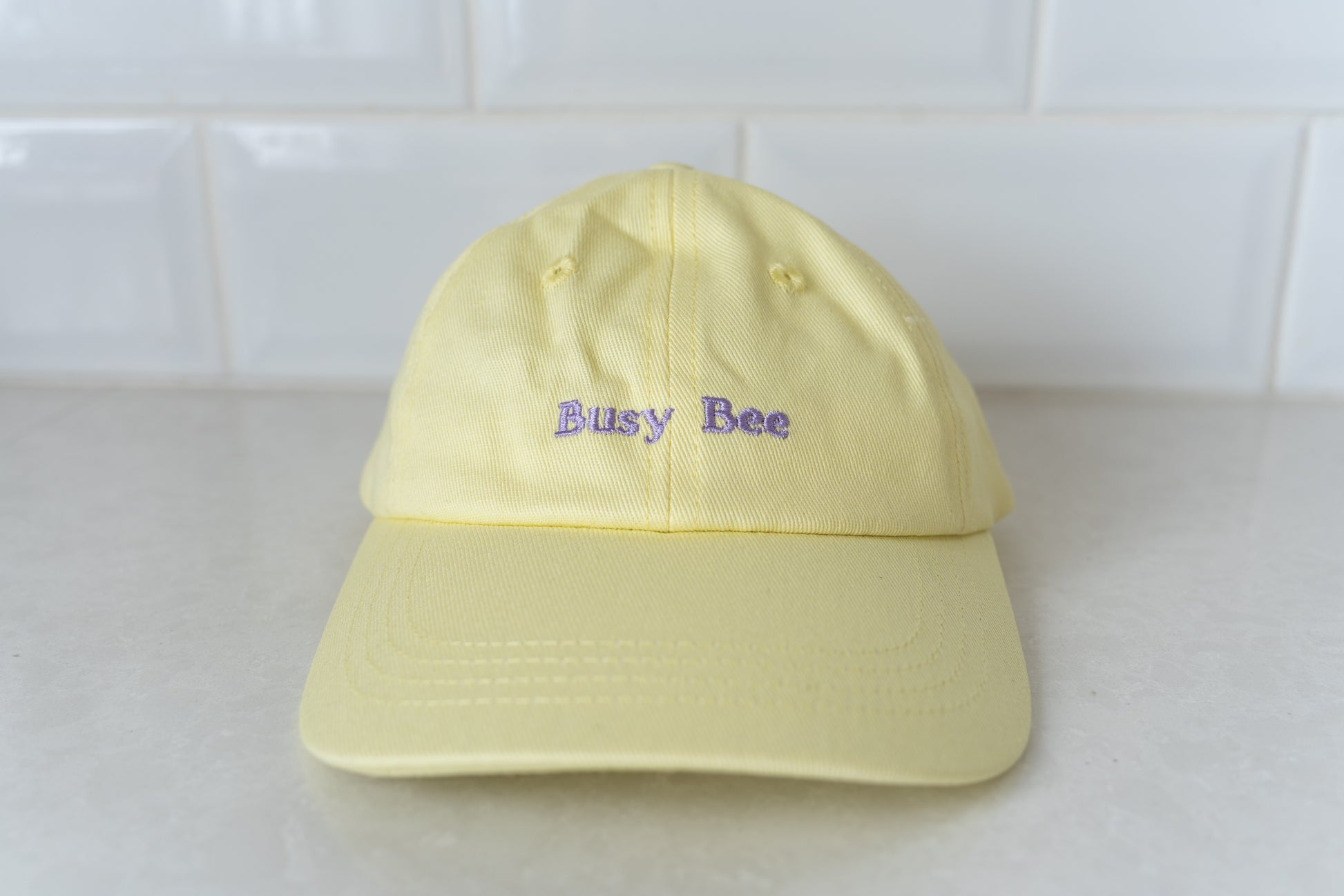 Yellow kids' hat with 'Busy Bee' embroidery, perfect for active children and outdoor play.