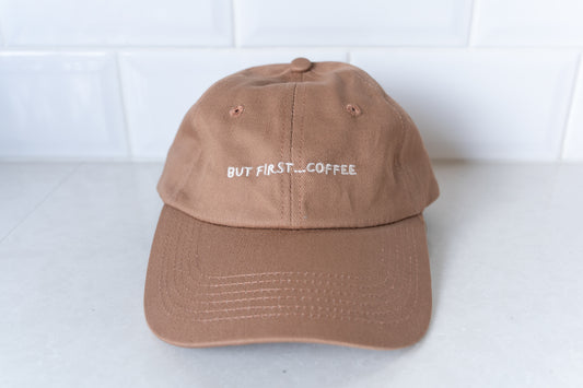 Brown dad cap with 'But First, Coffee' embroidered in white text on the front, perfect for coffee lovers.