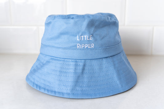 Front view of blue 'Little Ripper' bucket hat for kids with white embroidered text, designed for sun protection and outdoor play.