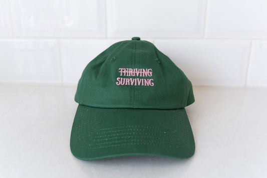 Dark green 'Thriving Surviving' hat for adults, perfect for a stylish and empowering accessory for parents.
